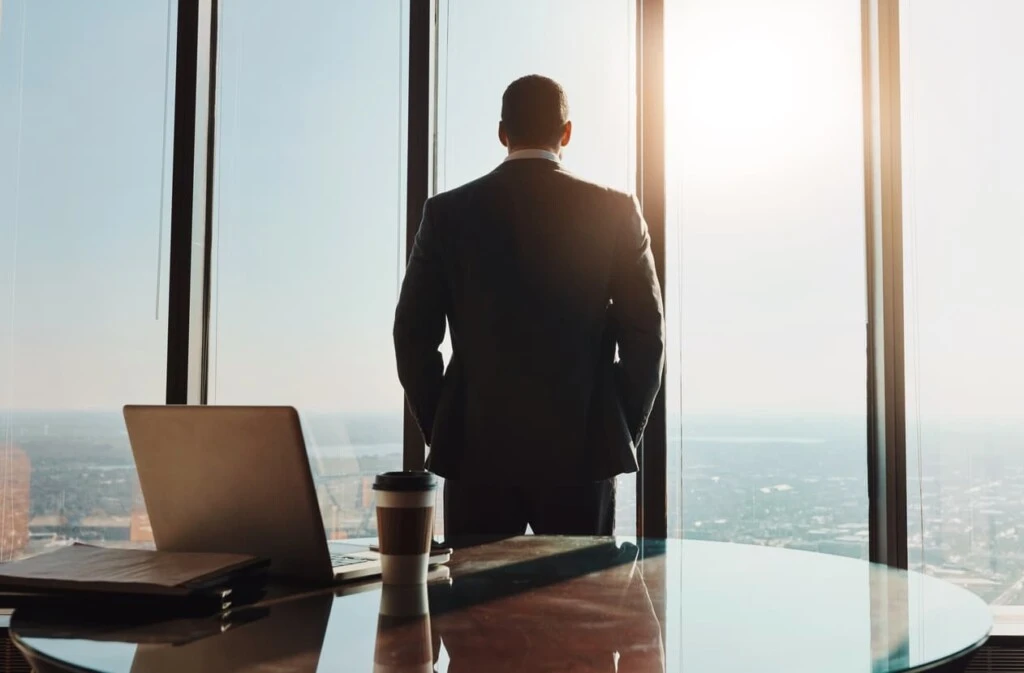Business, man and back thinking at window in office with city view for legal case ideas and solution. Law firm, thoughtful advocate and professional or contemplating client defense for court trial